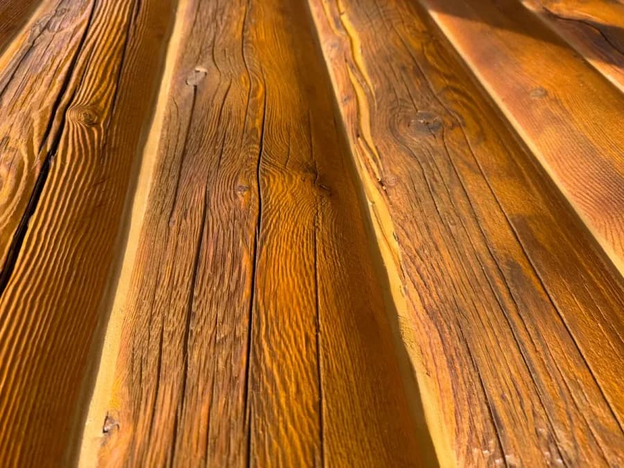 Close-up of log home showing surface damage from pressure washing with raised wood fibers and deep grain erosion